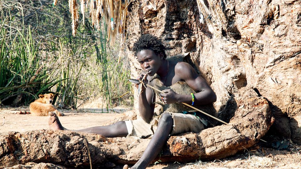 Ein junger Mann vom Volk der Hadza fertigt einen Bogen