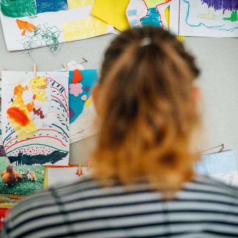 Christina S. in ihrer Wohnung, vor Bildern, die ihre Kinder gemalt haben