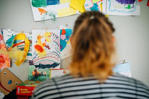 Christina S. in ihrer Wohnung, vor Bildern, die ihre Kinder gemalt haben