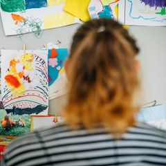 Christina S. in ihrer Wohnung, vor Bildern, die ihre Kinder gemalt haben