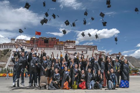 Heile Welt mit hochfliegenden Hüten der Studierenden in Lhasa mit dem Potala-Palast im Hintergrund.