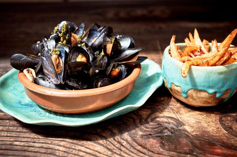 Moules frites  Zutaten: 5 große mehligkochende oder vorwiegend festkochende Kartoffeln, 2 kg küchenfertige frische Miesmuscheln, 4–6 Schalotten, 2 Knoblauchzehen, Olivenöl zum Anschwitzen, 400 ml trockener Weißwein, 1 TL Kräuter der Provence, 1 l Pflanzenöl, Salz  Zubereitung: Die Kartoffeln schälen, in dicke Stifte schneiden und beiseitestellen. Die Muscheln waschen, bereits geöffnete und angebrochene wegwerfen. Die Schalotten und den Knoblauch abziehen, fein hacken und in reichlich Olivenöl in einem Topf glasig anschwitzen. Mit dem Weißwein ablöschen und den Sud auf die Hälfte reduzieren. Dann die Muscheln und die Kräuter der Provence in den Topf geben. Alles gut umrühren und bei geschlossenem Deckel 10–15 Minuten kochen lassen. Ab und zu umrühren. Die im Anschluss an die Garzeit geschlossenen Muscheln aussortieren und wegwerfen. (Ungeöffnete Muscheln sind nicht zum Verzehr geeignet.) Die Kartoffelstifte in reichlich heißem Öl in einem Topf goldbraun frittieren. Dann mit einer Schöpfkelle aus dem Öl nehmen und auf Küchenpapier abtropfen lassen. Mit etwas Salz würzen. Die Muscheln mit dem Sud auf tiefen Tellern anrichten und mit den Pommes frites zusammen servieren
