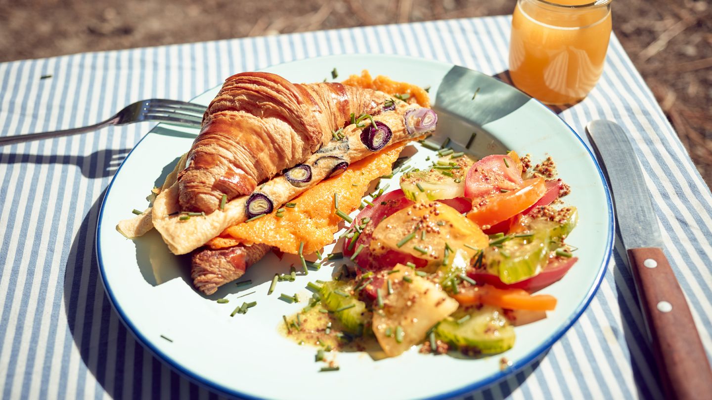 Croissant-Sandwich  Zutaten: Croissants (frisch oder vom Vortag), 150 g geriebener Cheddar, 2 reife Tomaten, 4 Frühlingszwiebeln, Olivenöl zum Anschwitzen, 2 Eier (Größe L), Salz, frisch gemahlener schwarzer Pfeffer   Zubereitung: Die Croissants aufschneiden und auf den Schnittflächen in einer beschichteten Pfanne ohne Fettzugabe anrösten. Danach auf Tellern beiseitelegen. Den Cheddar in die Pfanne geben, schmelzen lassen und kross anbraten. Den knusprig gebratenen Käse halbieren und auf den unteren Croissanthälften verteilen. Die Tomaten waschen, den Stielansatz herausschneiden und die Tomaten in Scheiben schneiden. Die Frühlingszwiebeln putzen, waschen und in Ringe schneiden. Etwas Olivenöl in der Pfanne erhitzen und die Frühlingszwiebeln darin anschwitzen. Dann die Eier aufschlagen, zufügen und alles zu einem Omelett braten. Mit Salz und Pfeffer würzen. Zum Anrichten das Omelett auf den Käse geben, die Tomatenscheiben darauf verteilen und die obere Hälfte der Croissants aufsetzen. Dazu passt Tomatensalat mit Schnittlauch, starker Kaffee und Orangensaft.