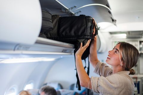 Eine Frau verstaut ihr Handgepäck im Flugzeug