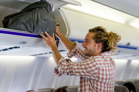 Ein Mann verstaut sein Handgepäck im Flugzeug