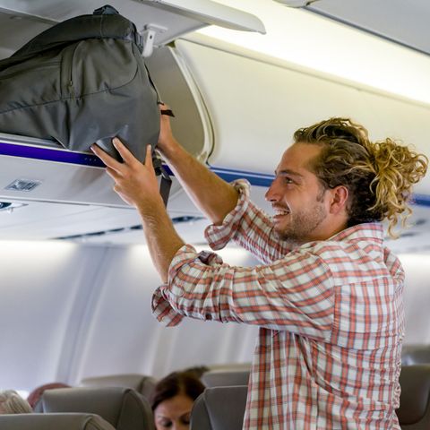 Ein Mann verstaut sein Handgepäck im Flugzeug