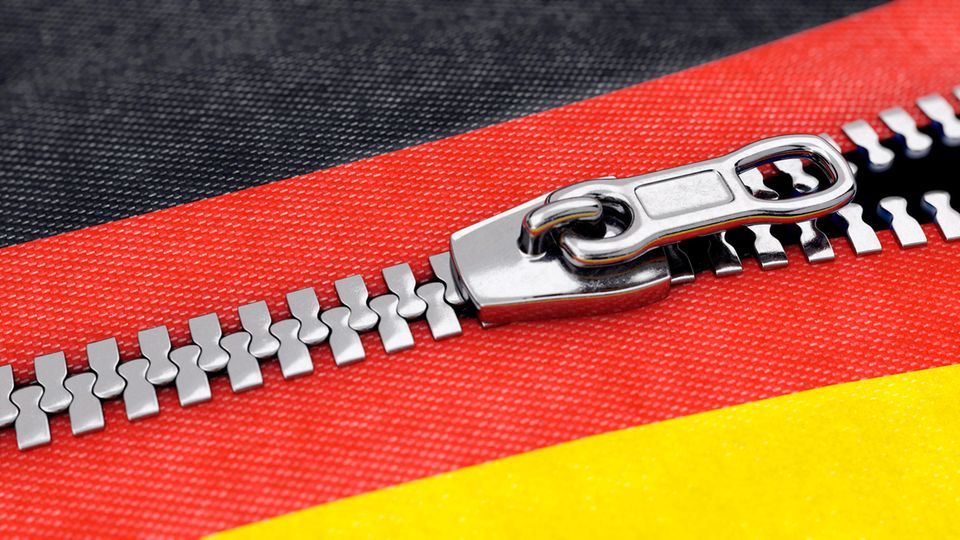 Ein Reißverschluss öffnet sich quer durch das Rot der Deutschland-Farben