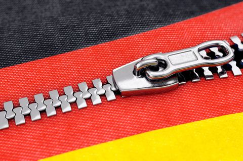 Ein Reißverschluss öffnet sich quer durch das Rot der Deutschland-Farben