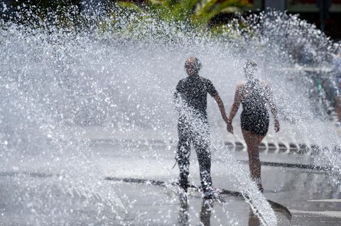 Ein Paar geht durch Wasserfontänen an einem sonnigen Tag