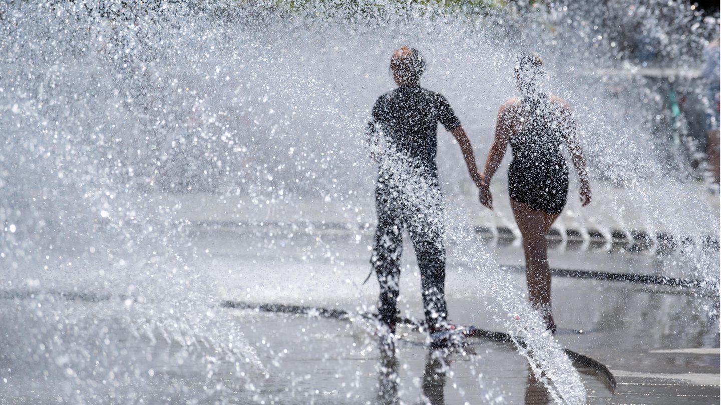 Ein Paar geht durch Wasserfontänen an einem sonnigen Tag