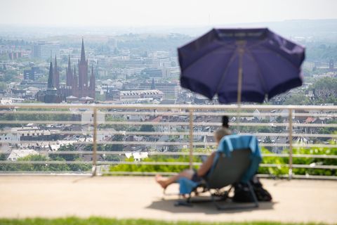 Eine Frau sitzt im Opelbad vor der Kulisse der Wiesbadener Innenstadt