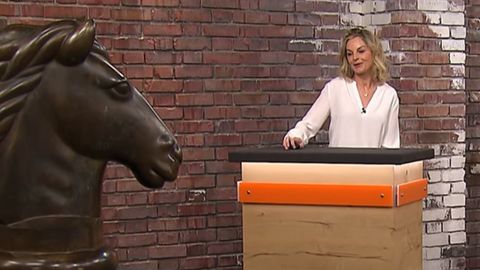 Susanne Steiger steht im Händlerraum von Bares für Rares in Pulheim neben der Bronzestatue eines Pferdekopfes