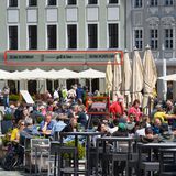 Wer hier genau hingeguckt hat, wird recht schnell den Hinweis auf Dresden auf dem kleinen, roten Schild entdeckt haben. An der Hausfassade im Hintergrund ist zudem der Schriftzug der Grill&Bar-Lokalität "Zum Schwan" zu erkennen. Kein Zweifel also, dass die Menschen hier auf dem Neumarkt an der berühmten Frauenkirche sitzen. Der ungefähre Ort bei Google Maps (hier noch mit einem anderen Lokal, da aus 2019).
