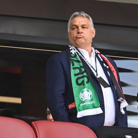 Viktor Orban schaut zufrieden. Ungarns Ministerpräsident steht mit einem um seine Schultern gelegten Fanschal an einem warmen Juni-Abend auf der Tribüne der Puskas Arena in Budapest.