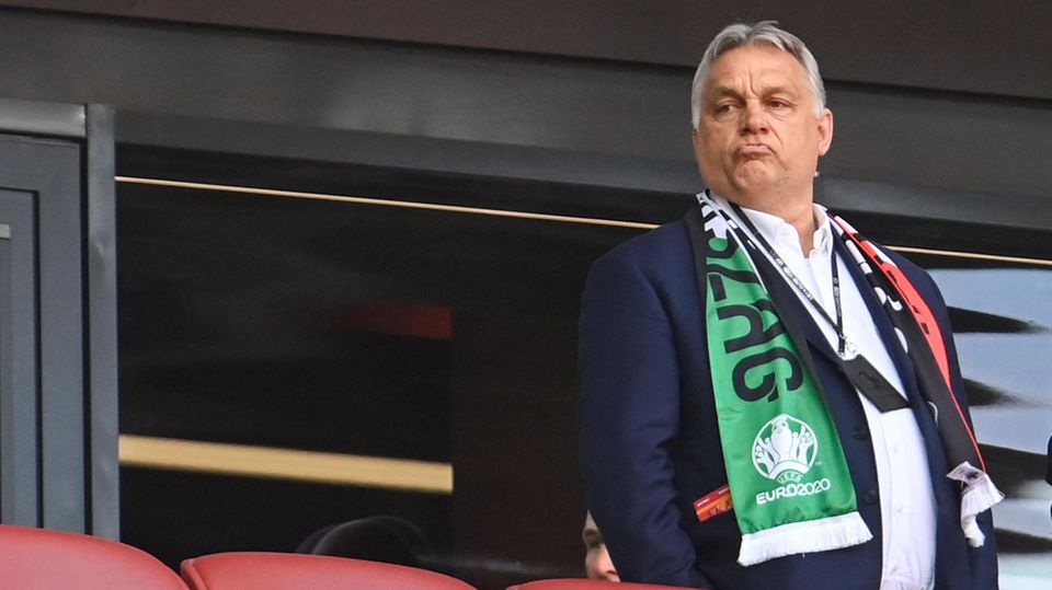 Viktor Orban schaut zufrieden. Ungarns Ministerpräsident steht mit einem um seine Schultern gelegten Fanschal an einem warmen Juni-Abend auf der Tribüne der Puskas Arena in Budapest.