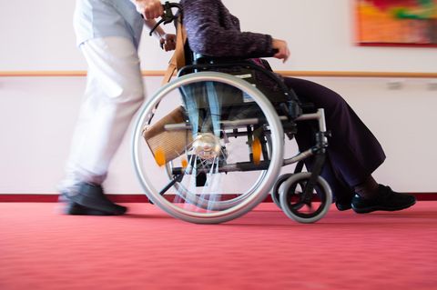 Altenpflege: Ein Pfleger schiebt eine Pflegeheimbewohnerin in einem Rollstuhl