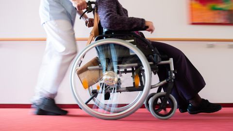 Altenpflege: Ein Pfleger schiebt eine Pflegeheimbewohnerin in einem Rollstuhl