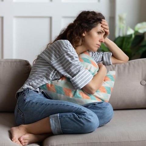 Long Covid Studie USA: Eine Frau sitzt auf einem Sofa und fasst sich an den Kopf