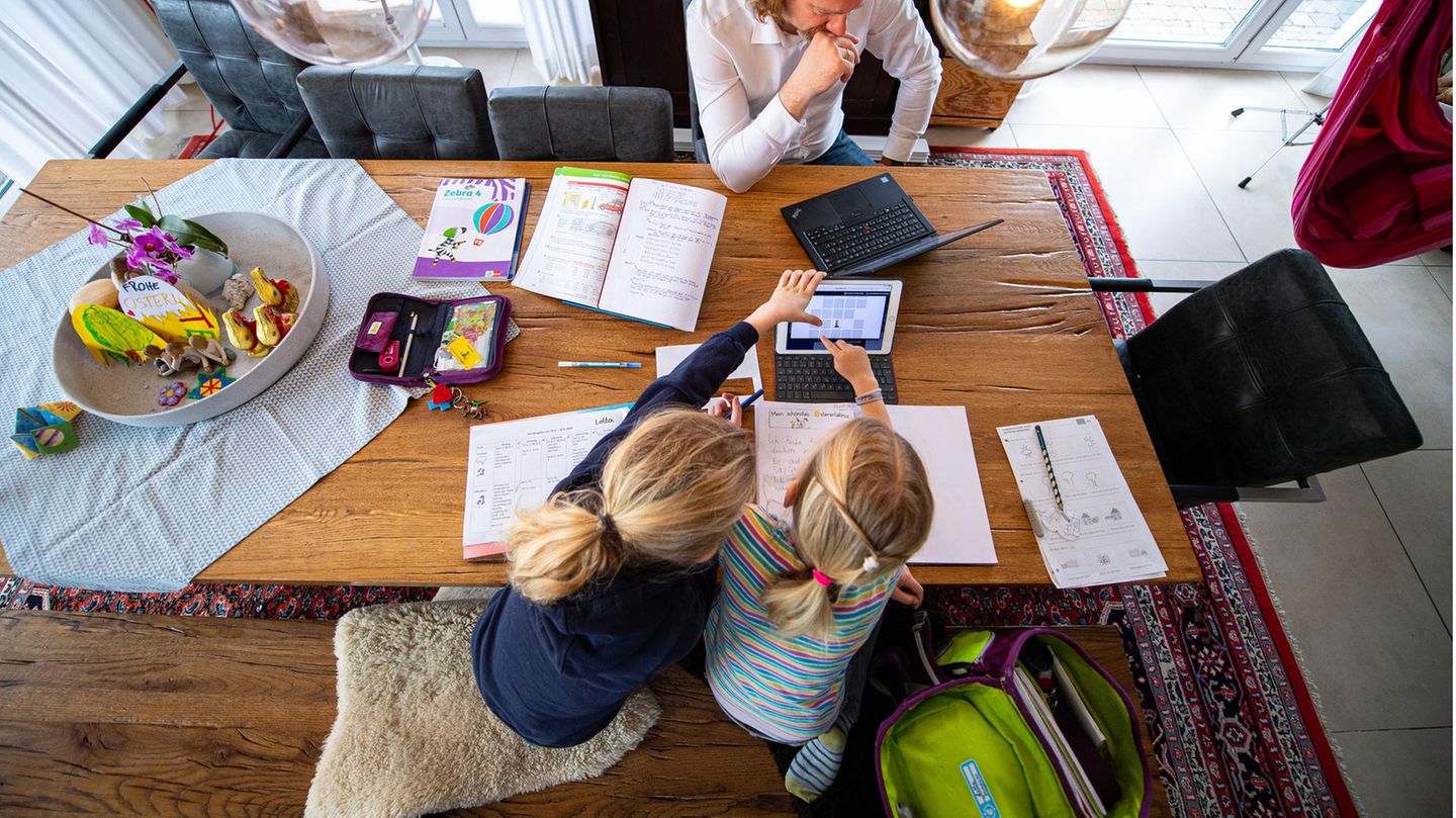 Zwei Schwestern machen im April 2021 ihre Schulaufgaben am Wohnzimmertisch.