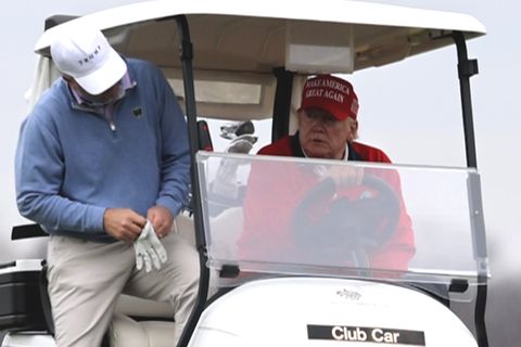Der ehemalige US-Präsident Donald Trump sitzt im Golfwagen.