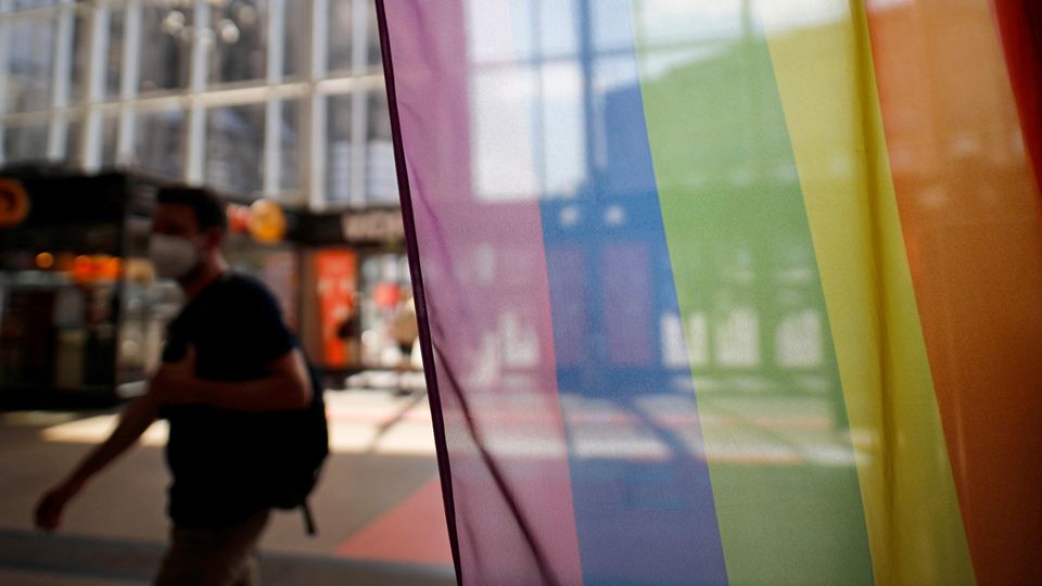 Vor dem Infoschalter der Deutschen Bahn im Kölner Hauptbahnhof stehen Regenbogenflaggen