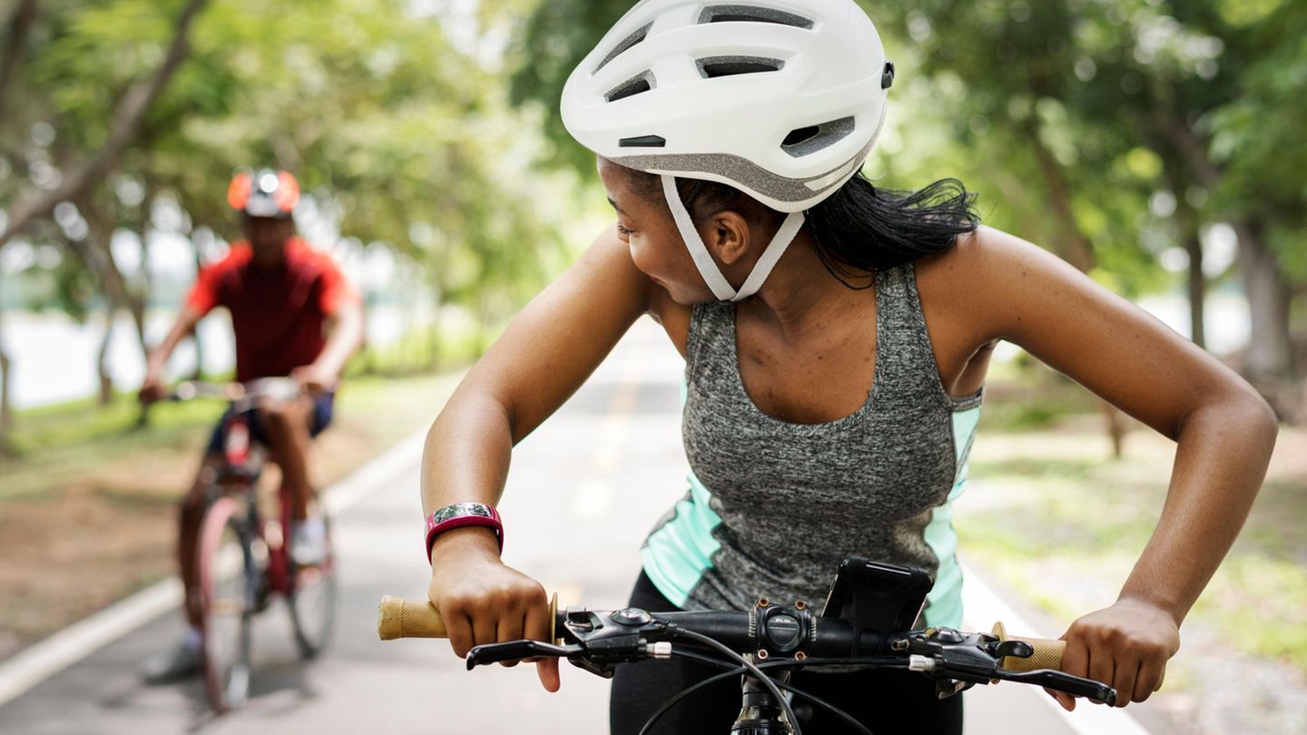 Eine Frau und ein Mann fahren Fahrrad und tragen Helme