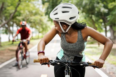 Eine Frau und ein Mann fahren Fahrrad und tragen Helme