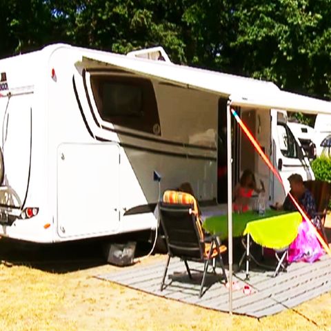 Familie sitzt vor ihrem Campingwagen