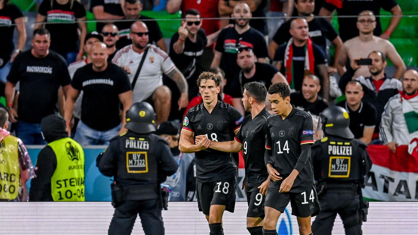 Leon Goretzka (l.), Kevin Volland und Jamal Musiala nach dem Tor zum 2:2, im Hintergrund die als gewaltbereit geltenden Anhänger der sogenannten "Carpathian Brigade" sowie Einsatzkräfte der Polizei
