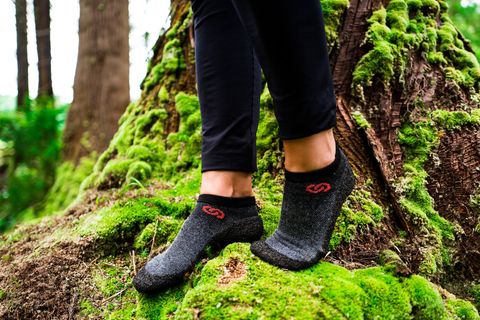 Sockenschuhe im Trend: Zwei Füße mit Sockenschuhen stehen auf vermoostem Baumstamm