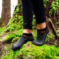 Sockenschuhe im Trend: Zwei Füße mit Sockenschuhen stehen auf vermoostem Baumstamm