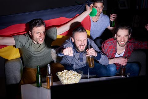 Fußball-Fans schauen sich ein Spiel im Fernsehen an und jubeln