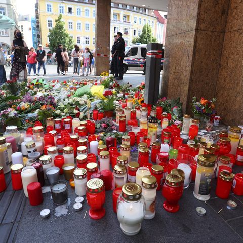 Blumen und Kerzen vor einem geschlossenen und abgesperrten Kaufhaus in der Innenstadt