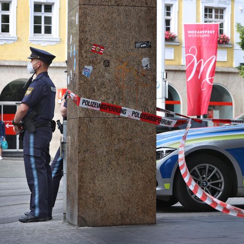 Polizisten stehen vor dem geschlossenen und abgesperrten Geschäft in der Innenstadt von Würzburg