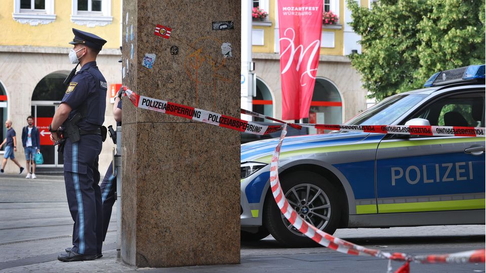 Polizisten stehen vor dem geschlossenen und abgesperrten Geschäft in der Innenstadt von Würzburg
