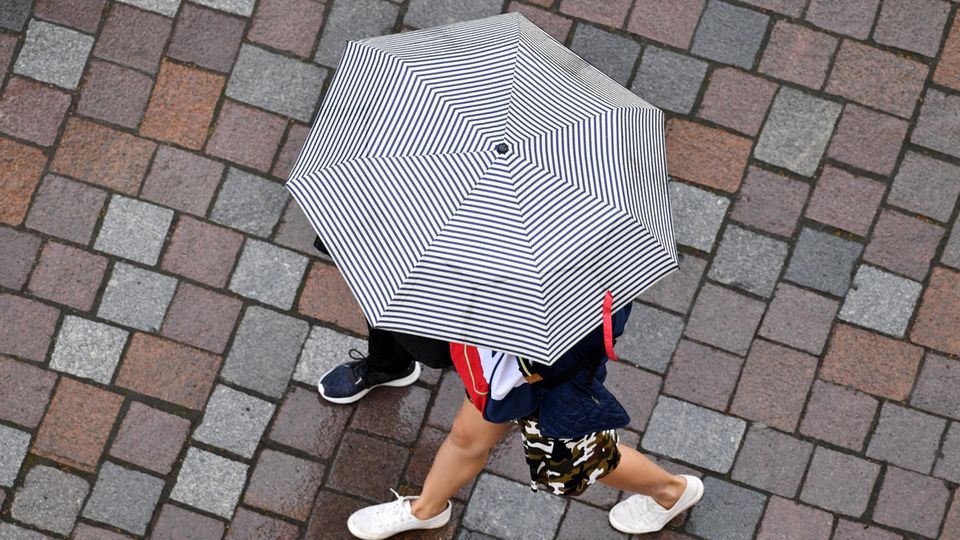 Symbolbild zum Siebenschläfer: Passanten gehen bei Regen in Potsdam spazieren.