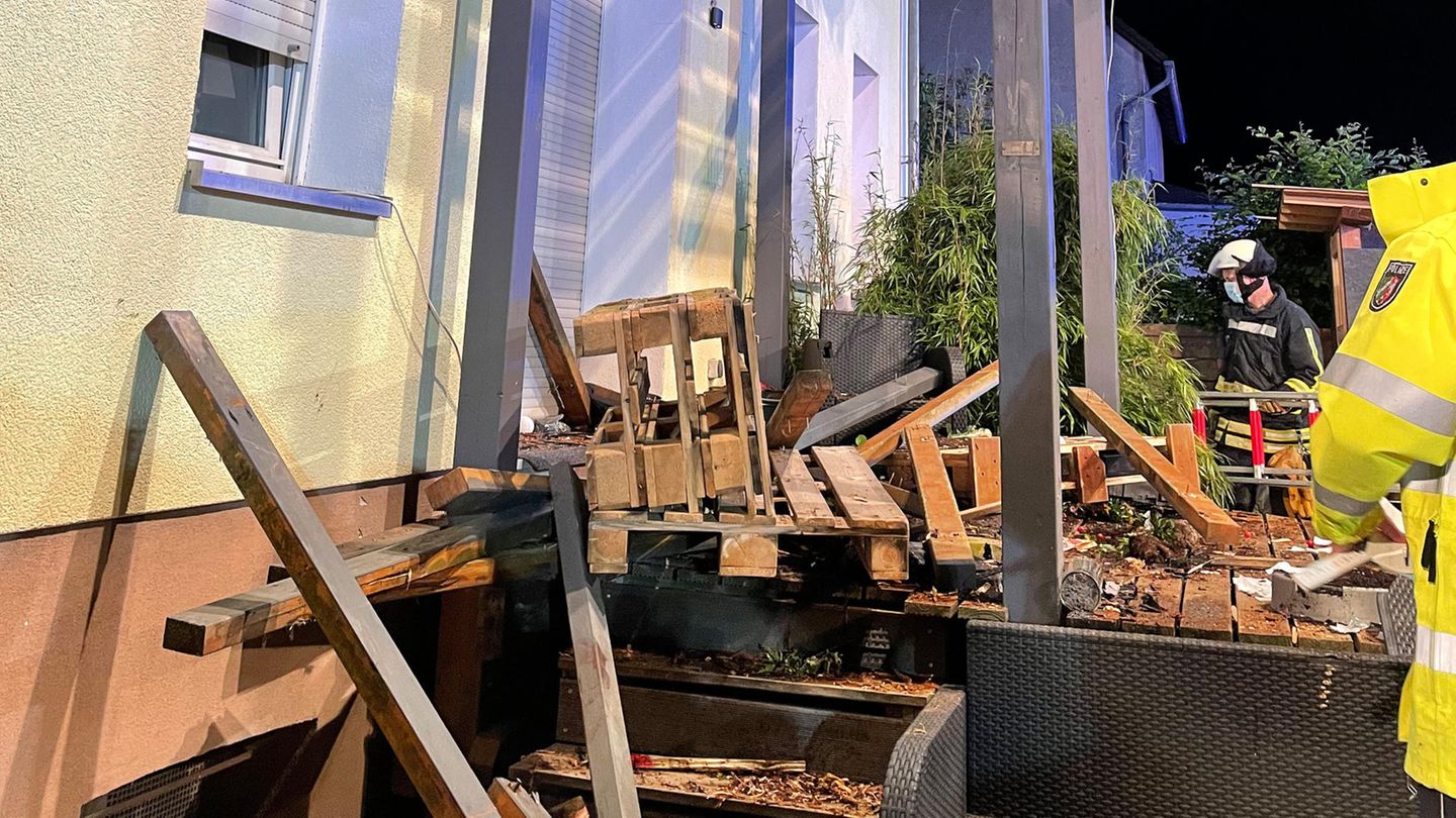 Rettungskräfte stehen neben den Trümmern eines Balkons aus Holz, der mit mehreren Menschen darauf eingestürzt ist.
