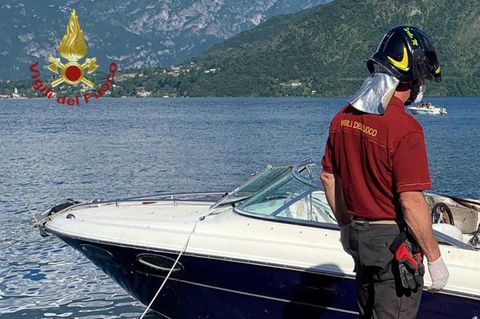 Ein Feuerwehrmann steht neben einem Motorboot, dass auf dem Comer See verunfallt war