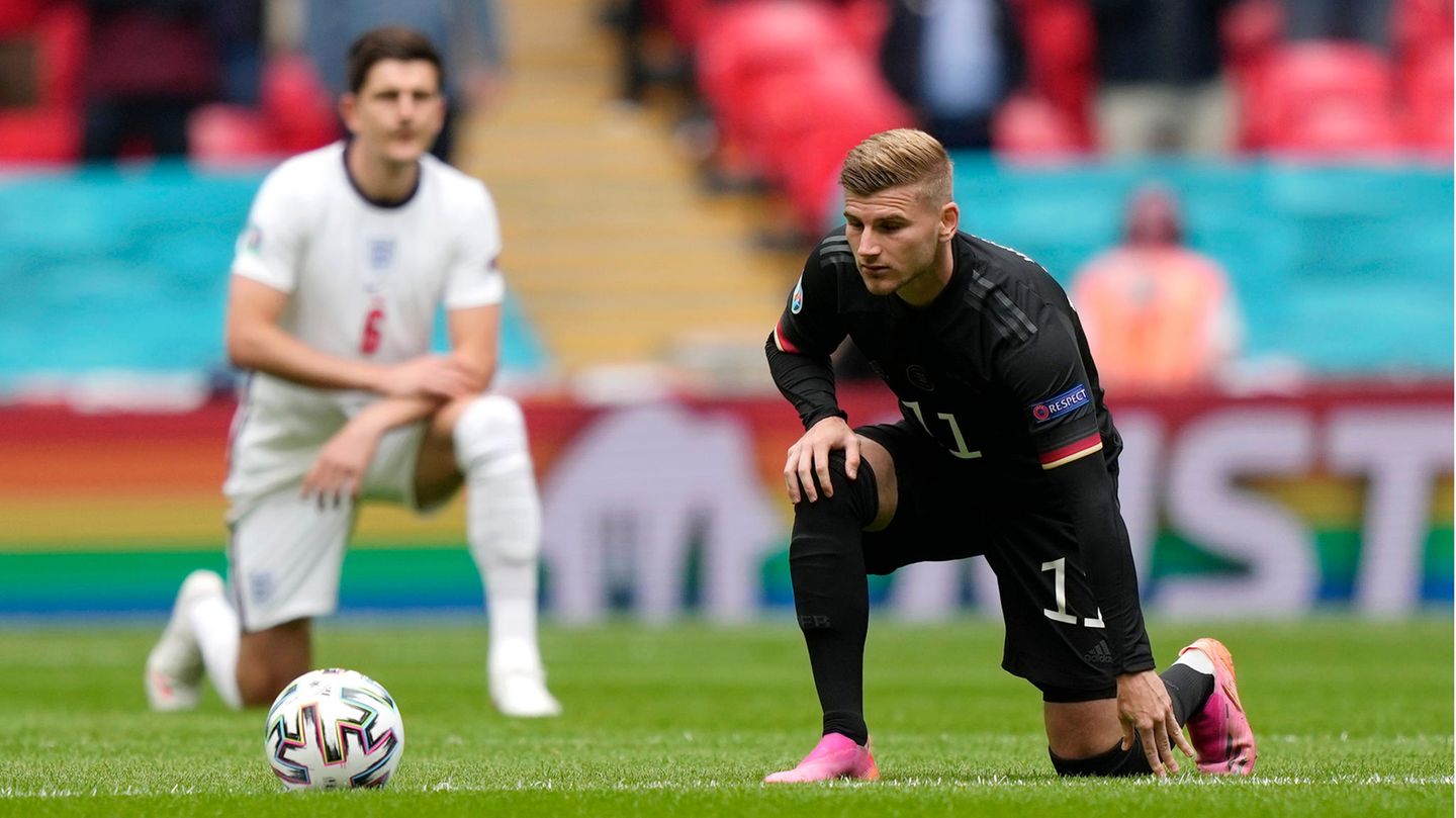 Ein blonder Fußballer im schwarzen Dress des DFB-Teams kniet mit links auf dem Rasen