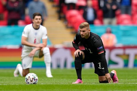 Ein blonder Fußballer im schwarzen Dress des DFB-Teams kniet mit links auf dem Rasen