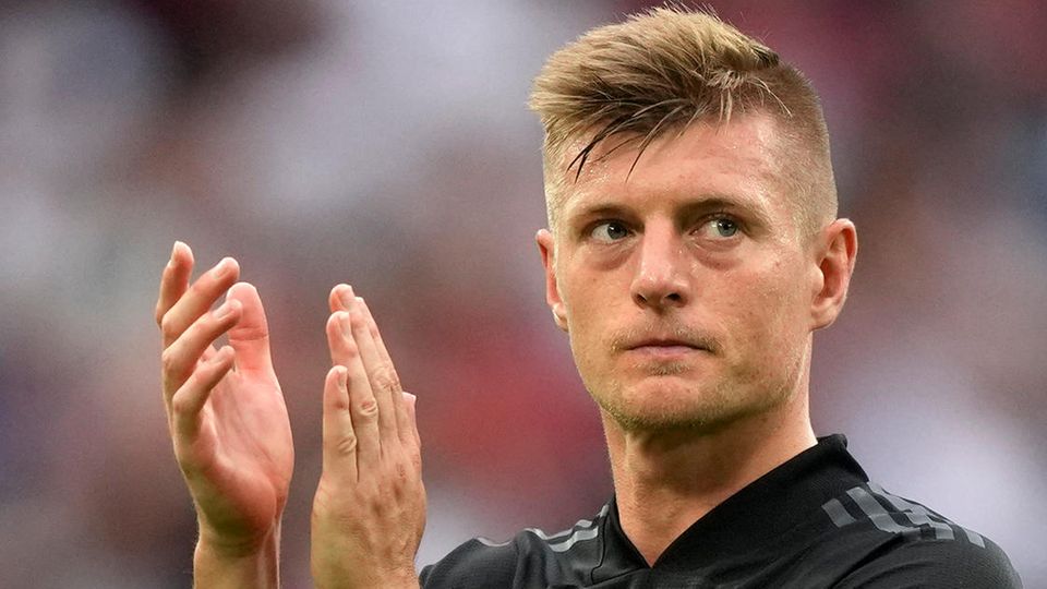 Wearing a black DFB jersey, Toni Kroos applauds the fans while disappointment is written on his face
