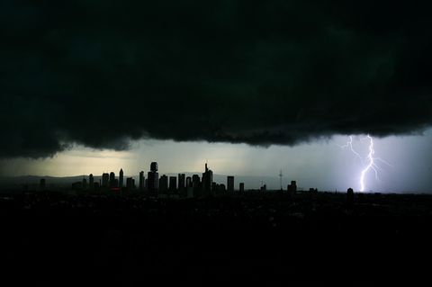 Tiefschwarze Gewitterwolken verdunkeln den Himmel über der Frankfurter Innenstadt, während sich ein Blitz entlädt