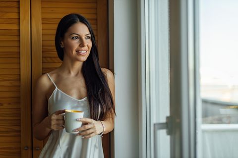 Frau im Slip Dress mit Becher in der Hand