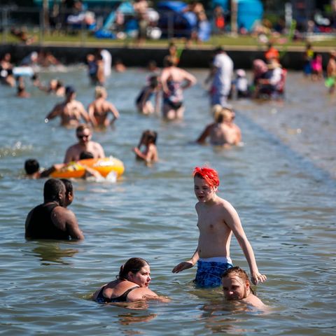 Badegäste kühlen sich an einem Strand von der Hitze ab