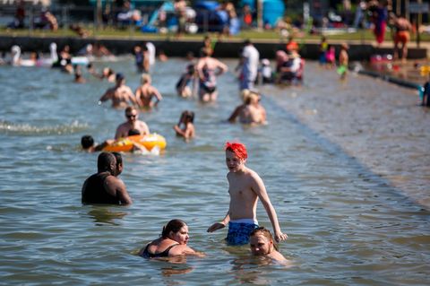 Badegäste kühlen sich an einem Strand von der Hitze ab