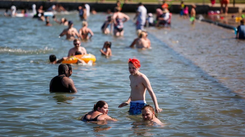 Badegäste kühlen sich an einem Strand von der Hitze ab