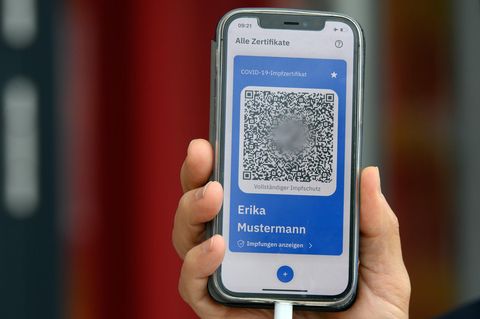 Eine Hand hält ein Mobiltelefon mit einem QR-Code