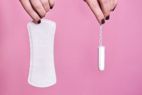 Zwei Hände halten jeweils eine Binde und einen Tampon