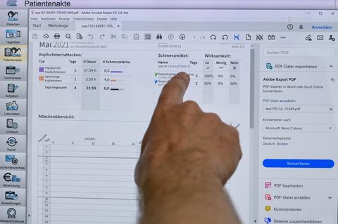 Eine Hand zeigt auf Eintragungen auf einem Computerbildschirm