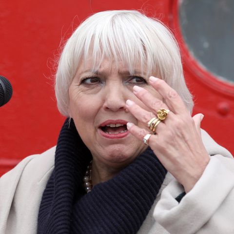 Claudia Roth mit erhobener Hand vor einem Mikrofon